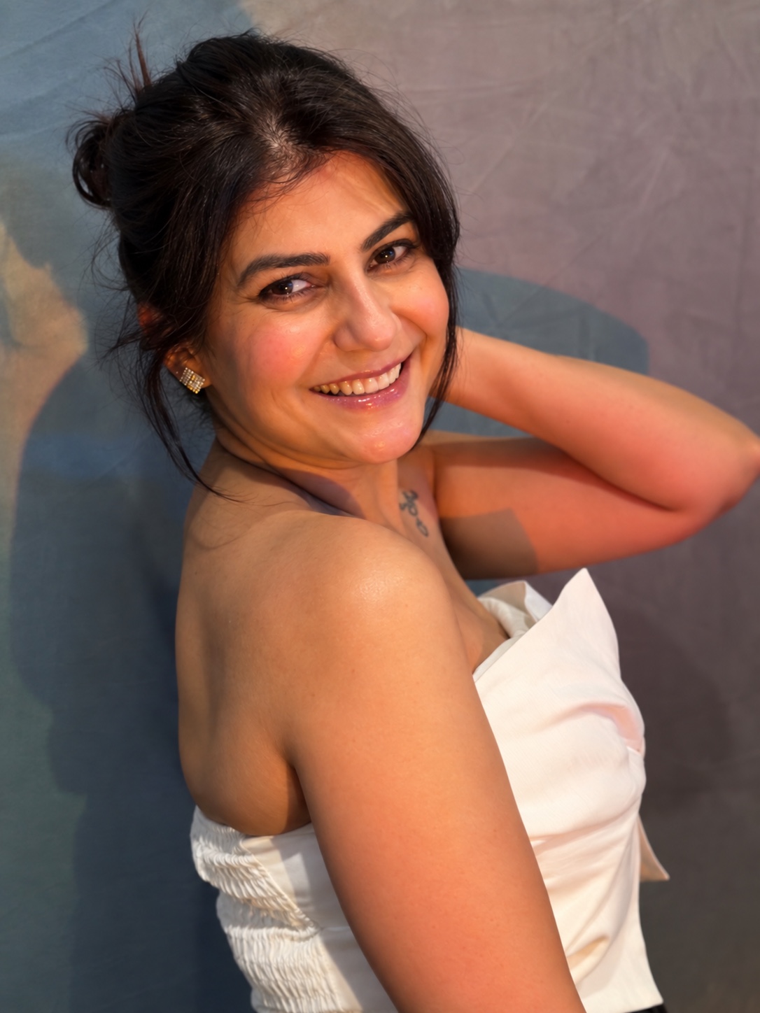 Moon Sheoran smiling over her shoulder in an elegant white bow top